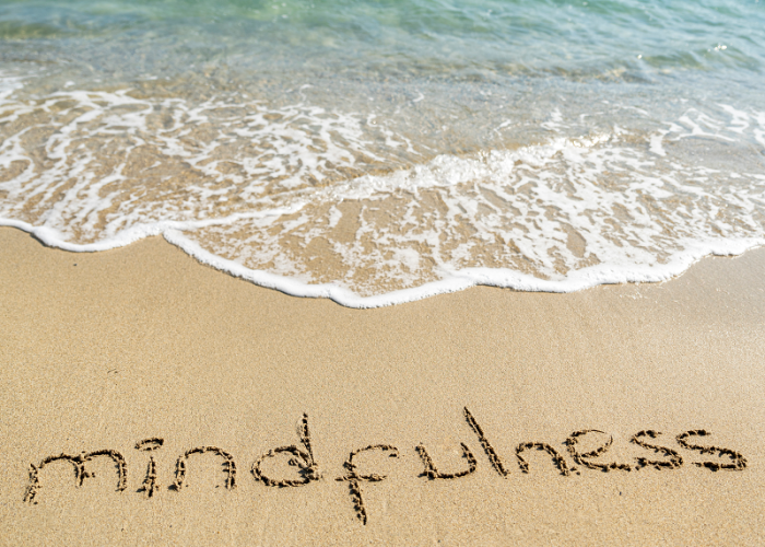 a picture of the word mindfulness in the sand that represents the benefits of massage and meditation