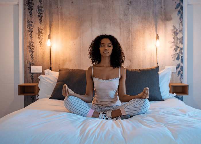 A woman meditating on her bed